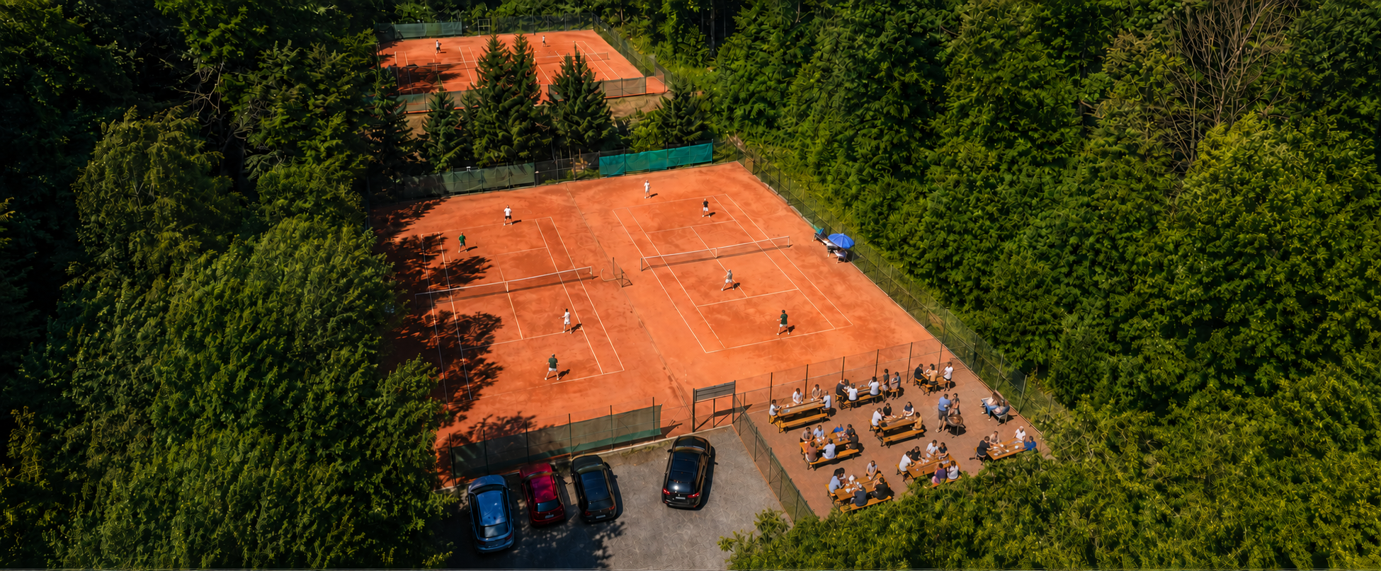 Belebte Luftaufnahme der Tennisplätze des TC Garitz mit Spielern in Vereinskleidung und Zuschauern